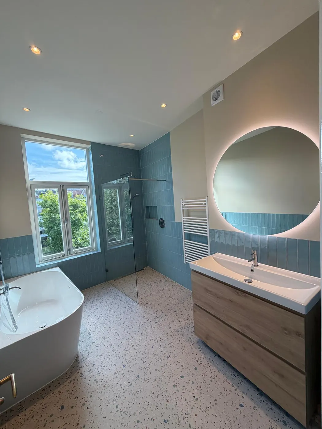 Badkamer met vrijstaand bad en ronde spiegel